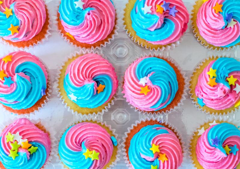 12 cupcakes with pink and blue icing, along with yellow stars