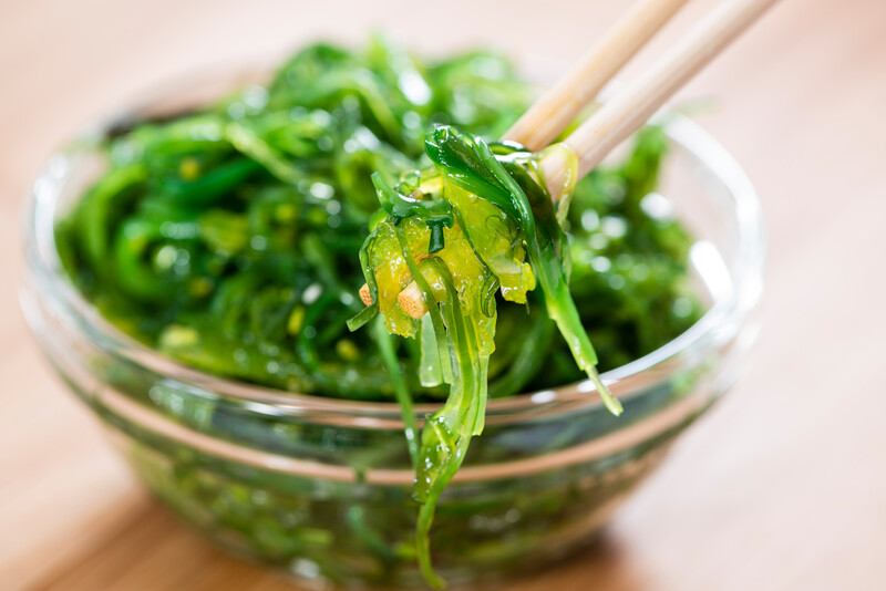 15 Best Foods Iodine | Food For Net A transparent bowl of seaweed with chopsticks in it rests on a wooden table.