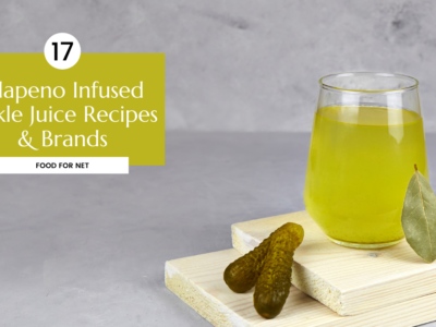 A glass of jalapeno infused pickle juice on a raised set of blocks, next to two pickles
