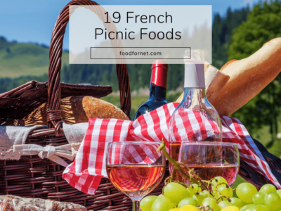 An outdoors picnic with a picnic hamper, fresh fruit, and wine, highlighting French picnic foods