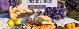 A selection of romantic picnic foods, including croissants, pretzels, and wine, surrounded by fruit and lavender.