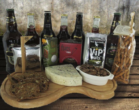 A line of beer bottles behind a selection of snacks and then a golf course shaped cutting board with various snacks on it. 