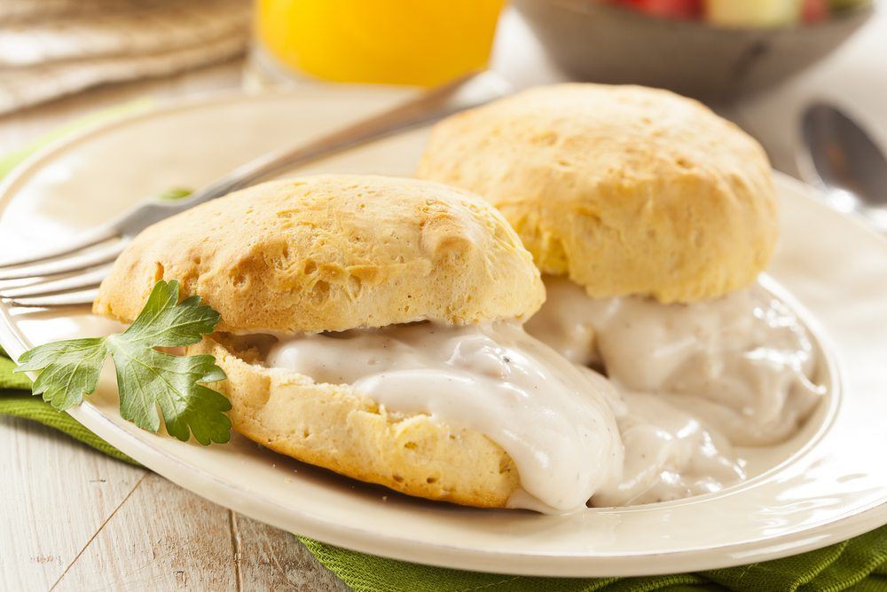 A white plate with two large biscuits and plenty of white gravy