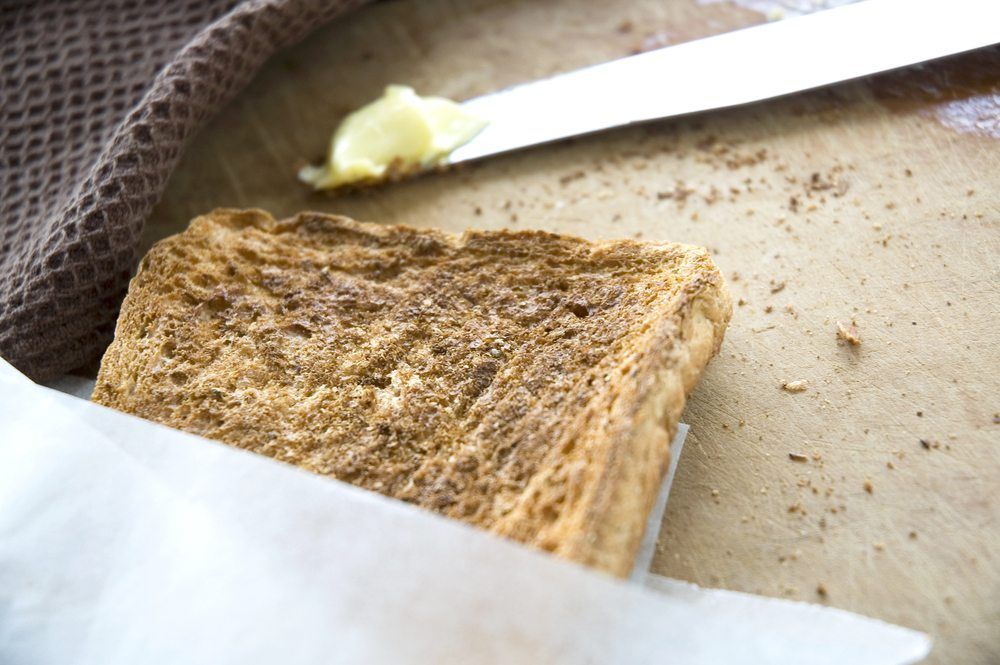 A wooden table with toast and butter on a knife