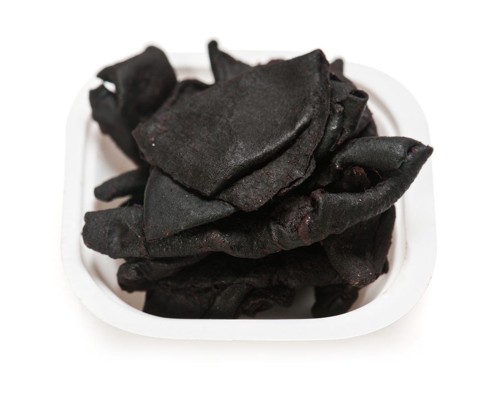 A white dish on a white table, containing dried kokum