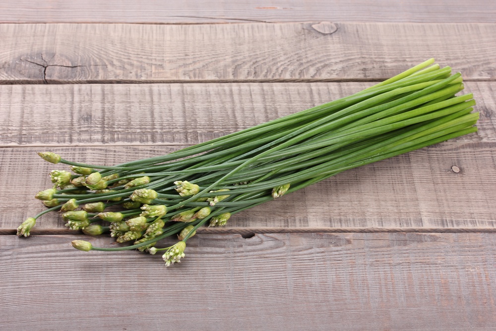 A collection of Chinese flowering leeks on a wooden board