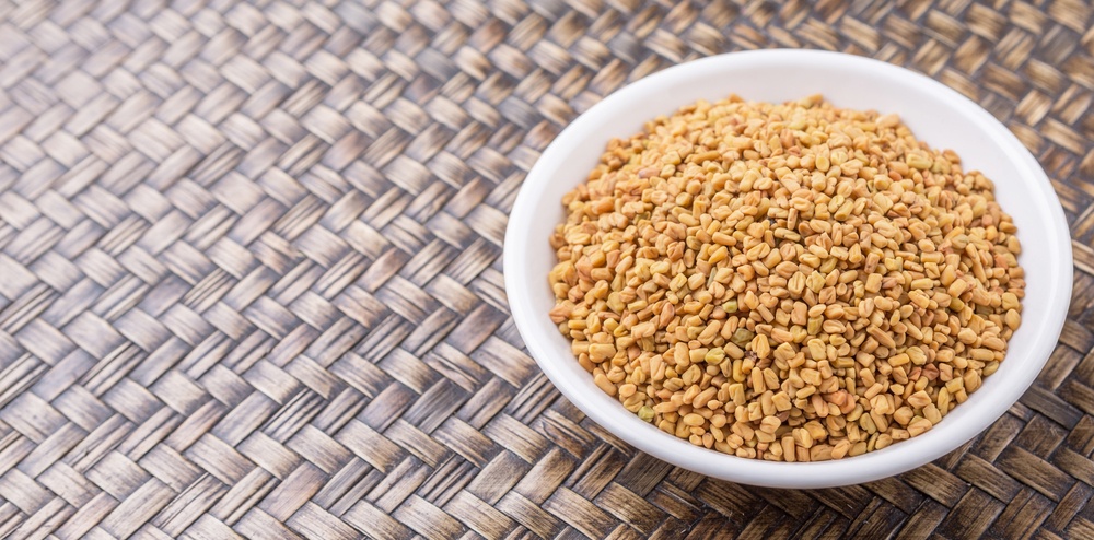 A white bowl of fenugreek on a hatched table