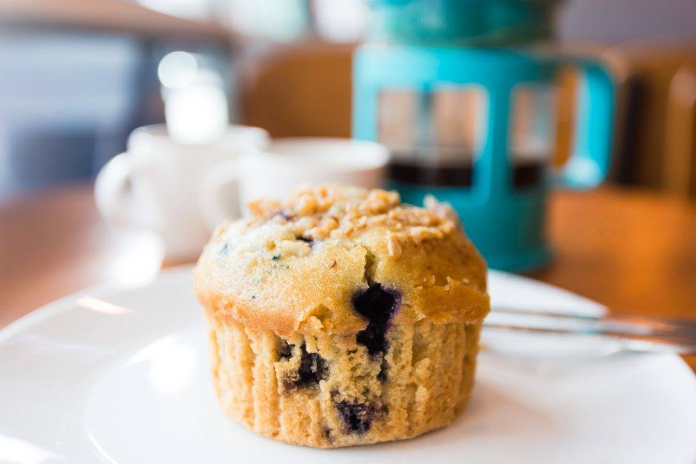 A white plate with a blueberry muffin 