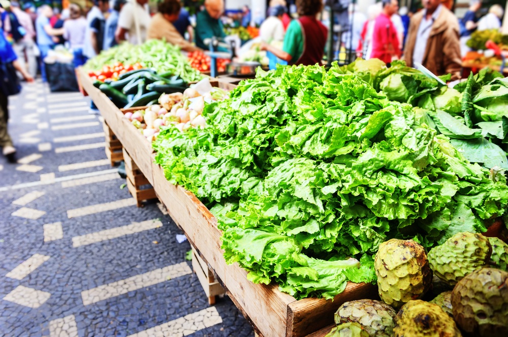 A farmer's market with many vegetables piled high, including some regular vegetables and some exotic ones. 