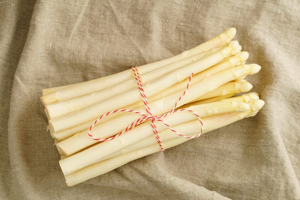 A bundle of white asparagus tied with a red and white string on a piece of cloth