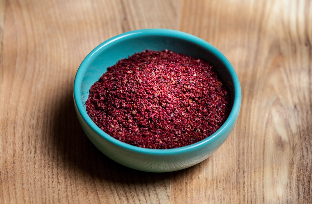 A light blue bowl containing dried sumac