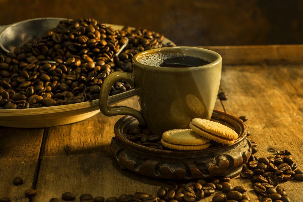 A mug that contains a Karsk cocktail, next to some cookies and many coffee beans