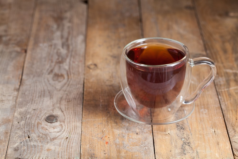 A glass mug containing a gunfire cocktail on a wooden table