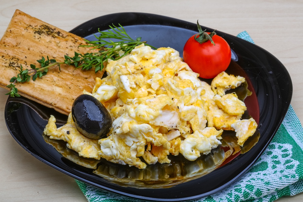 A black plate with plenty of scrambled eggs, plus toast