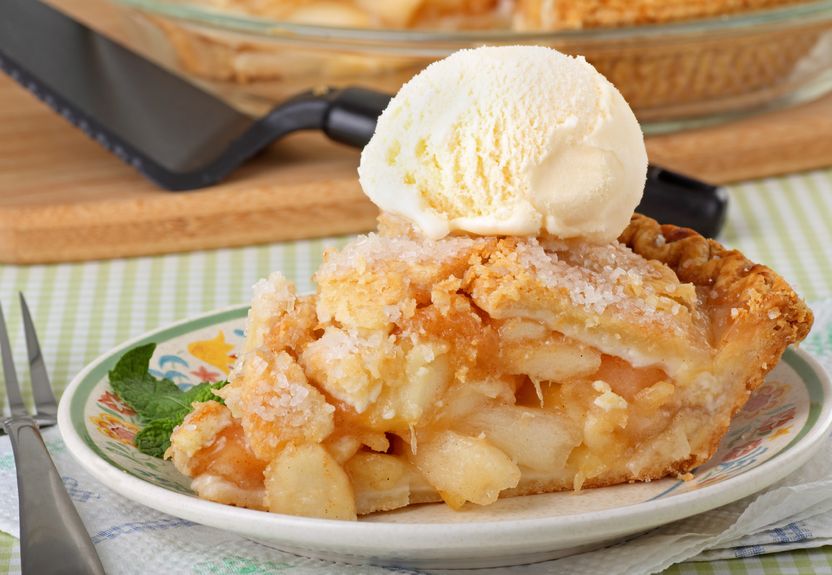 A white plate with a large slice of apple pie and vanilla ice cream