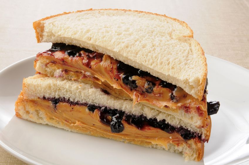 A white plate with two large peanut butter and jelly sandwiches 