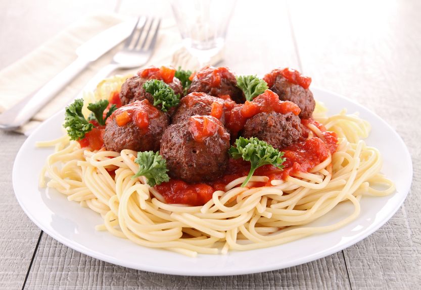 A white plate with spaghetti, meatballs, and tomato sauce