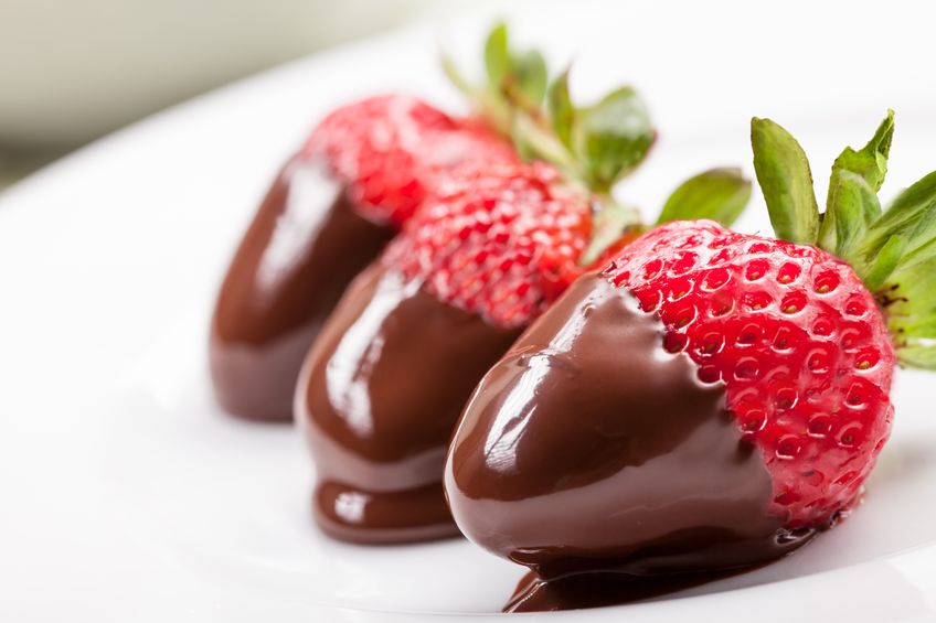 A white plate with three strawberries dipped in chocolate