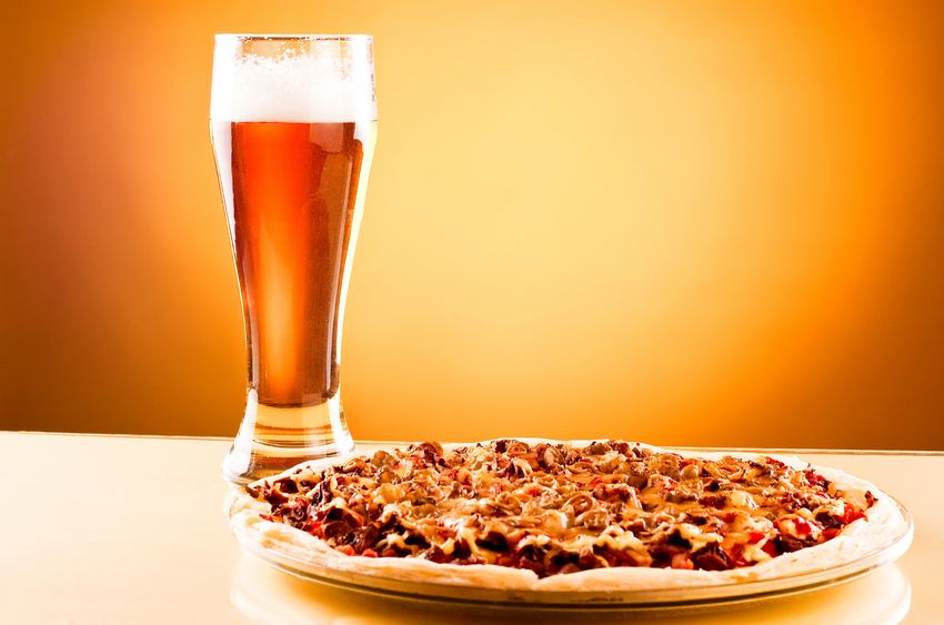 A table with a pizza and a beer 