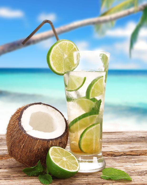 A glass with a lime and coconut cocktail, next to a coconut