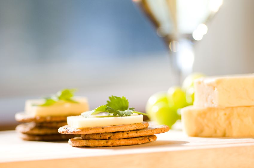 Stacks of crackers topped with cheese, next to more cheese