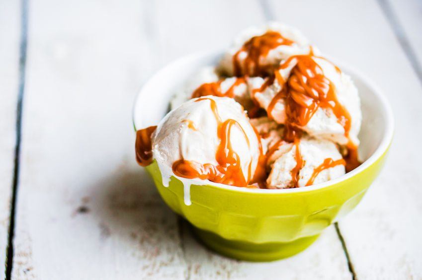 A light green bowl filled with ice cream and caramel sauce