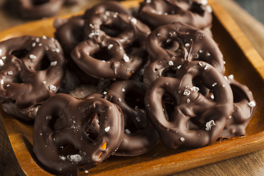 A wooden tray with chocolate covered pretzels that are topped with rock salt