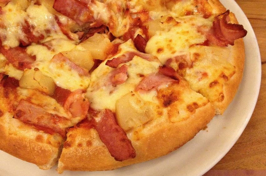 A white plate with a pineapple and ham pizza