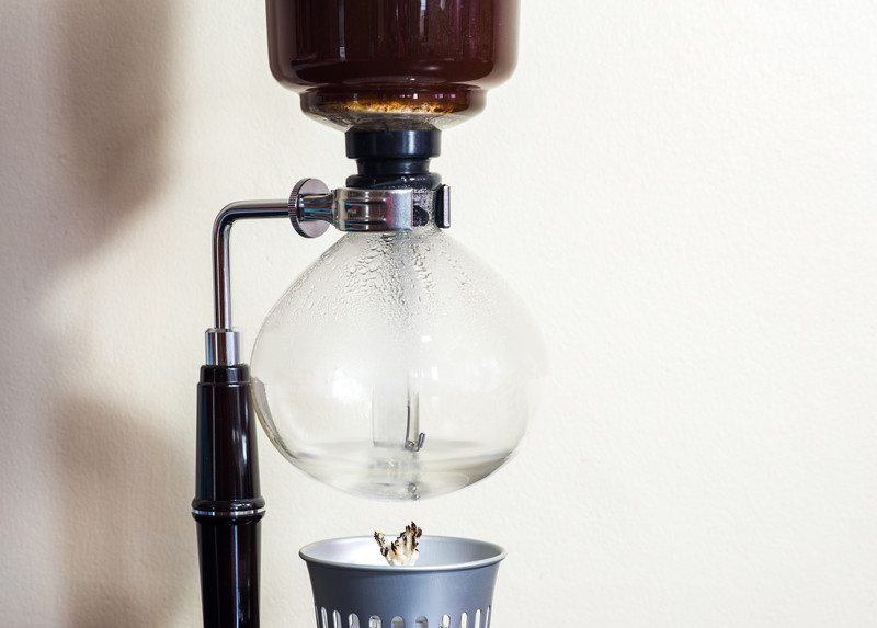 craft coffee being heated by wick and fire on a vacuum coffee pot