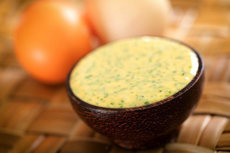 Paleo Mayonnaise sitting in a wooden bowl with eggs in the background