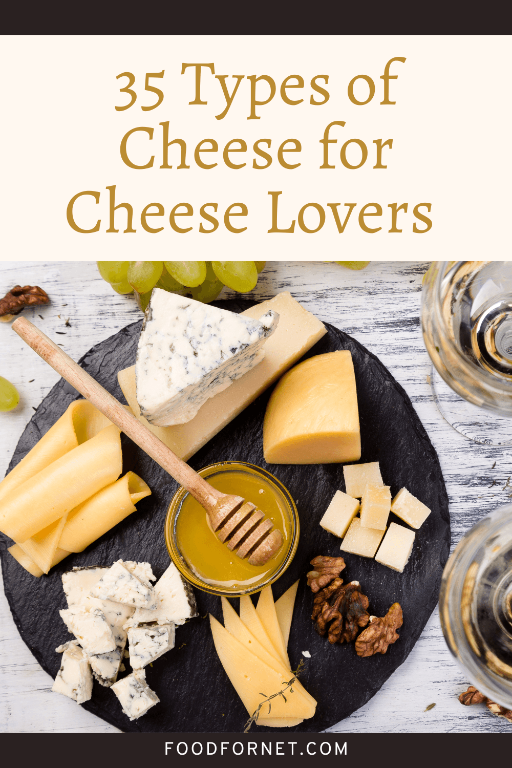 A black plate with a collection of different types of cheese, plus a shallow glass dish of honey