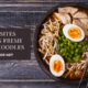 A black bowl containing cooked ramen with eggs, noodles, meat, and chopsticks