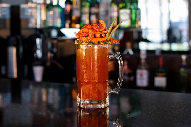 A Bloody Maria cocktail with a complex garnish on a bar