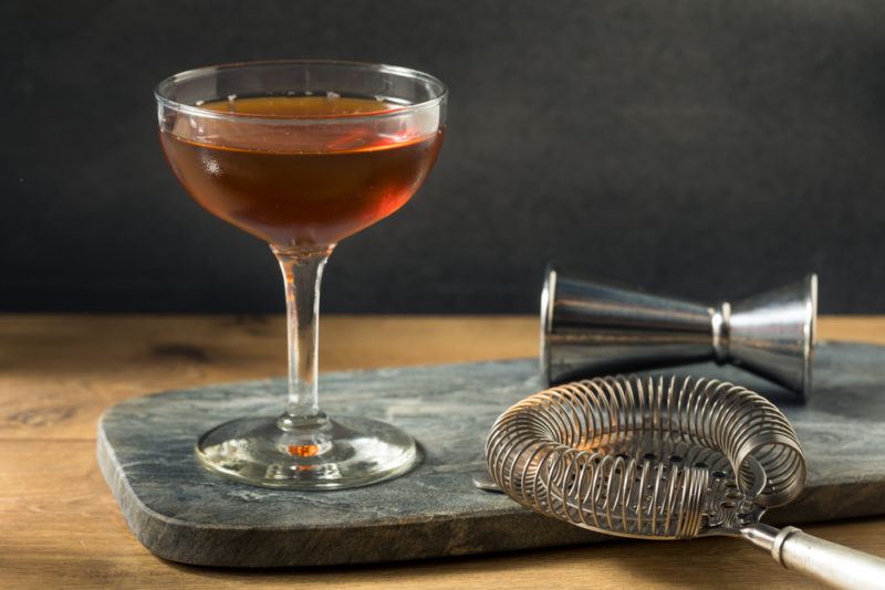 A Brooklyn cocktail on a slate board next to a cocktail jigger