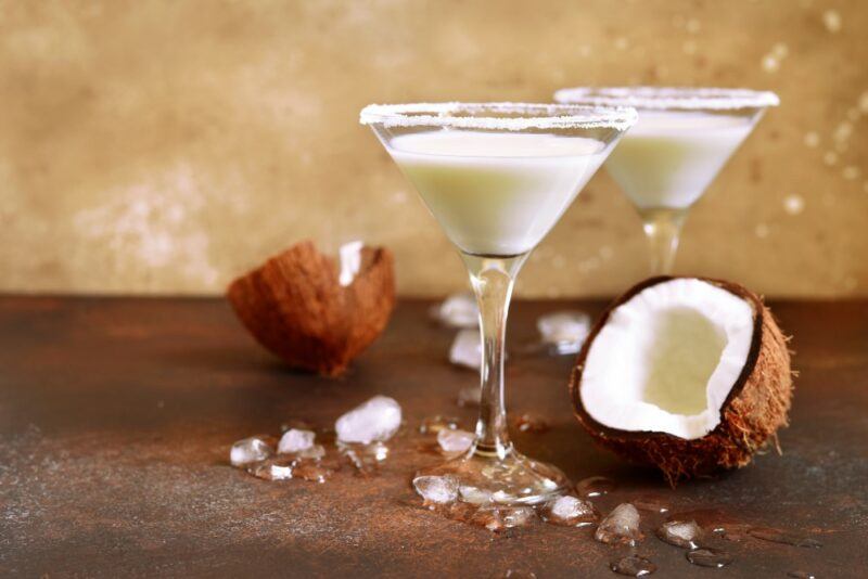 Two martini glasses containing a Don Roderico coconut cocktail on a brown table