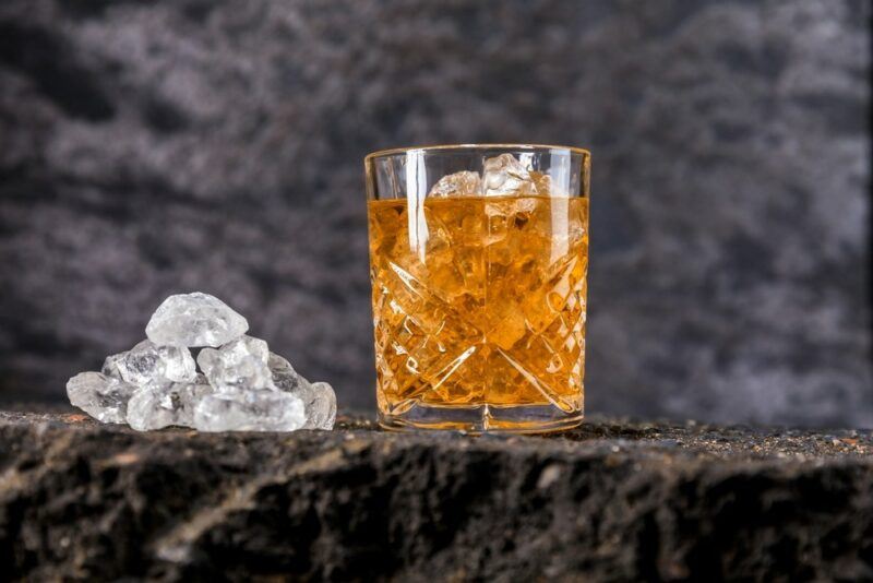 A pile of ice, next to a glass containing a Fireball smash cocktail