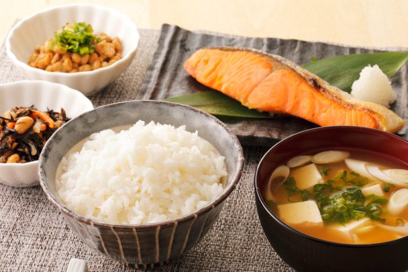 A Japanese style breakfast that includes rice, soup, fish and other ingredients