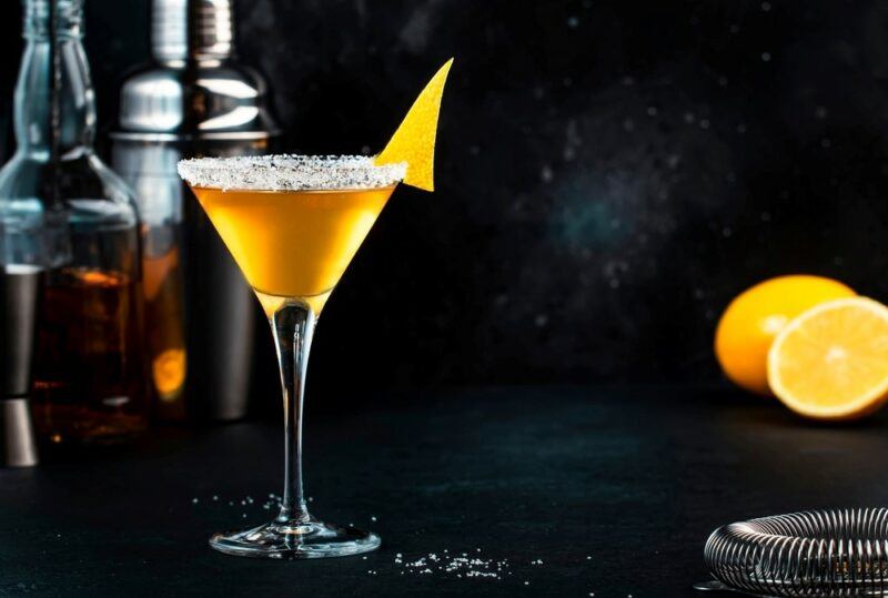 A martini cocktail containing a Lady's Sidecar cocktail next to some citrus fruit and spirits