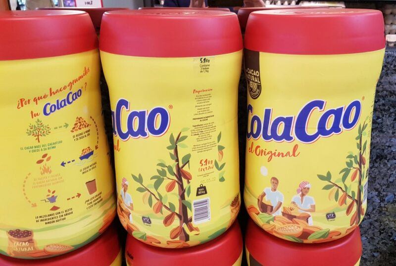 Containers of a chocolate Spanish drink called Cola Cao. The containers are yellow with red lids.