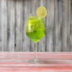 A single glass containing Tokyo iced tea garnished with a piece of lemon