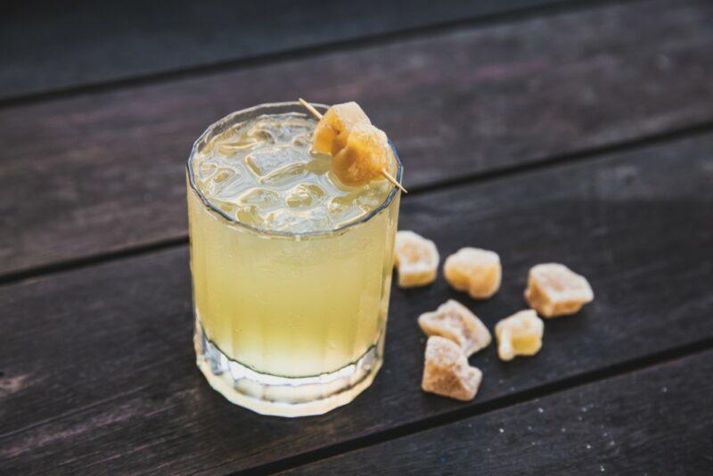 A single glass containing a White Claw honey mule cocktail with ginger as a garnish and on the table