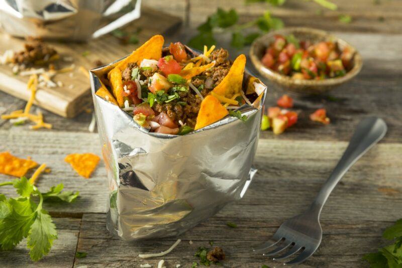 A metallic bag that contains tacos and toppings, with more ingredients in the background