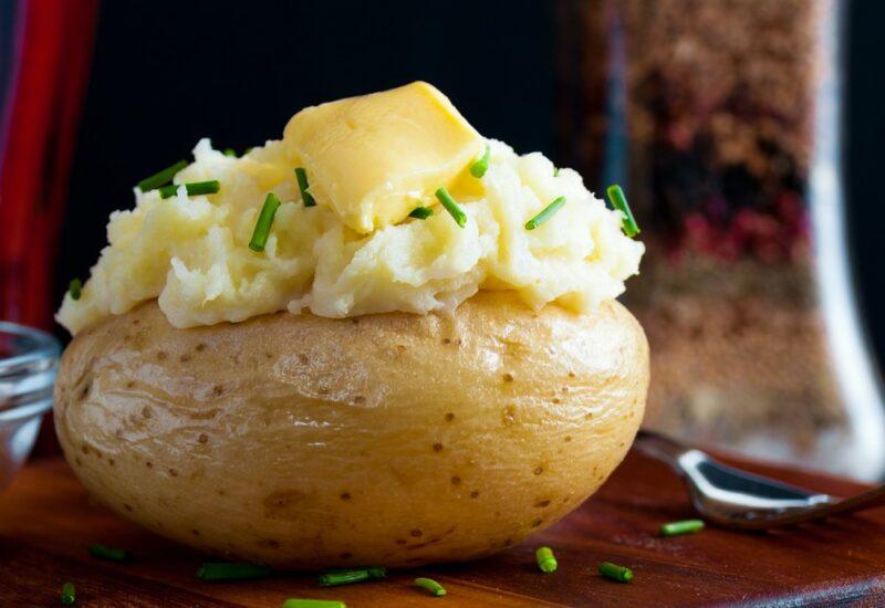 A single baked potato with mashed potato on the top and some butter