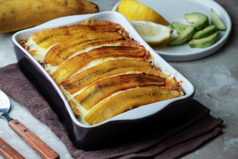 A baking dish that contains a layered plantain dish called pinon