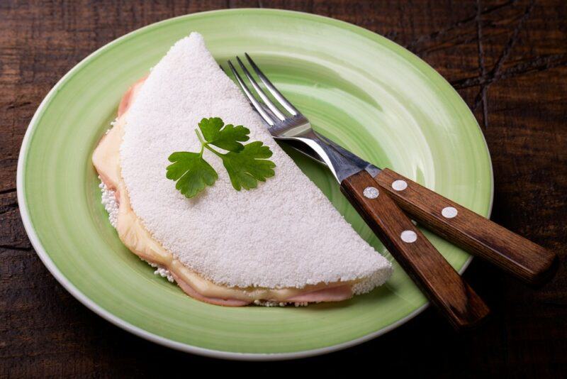 A green plate with a bammy next to a knife and a fork