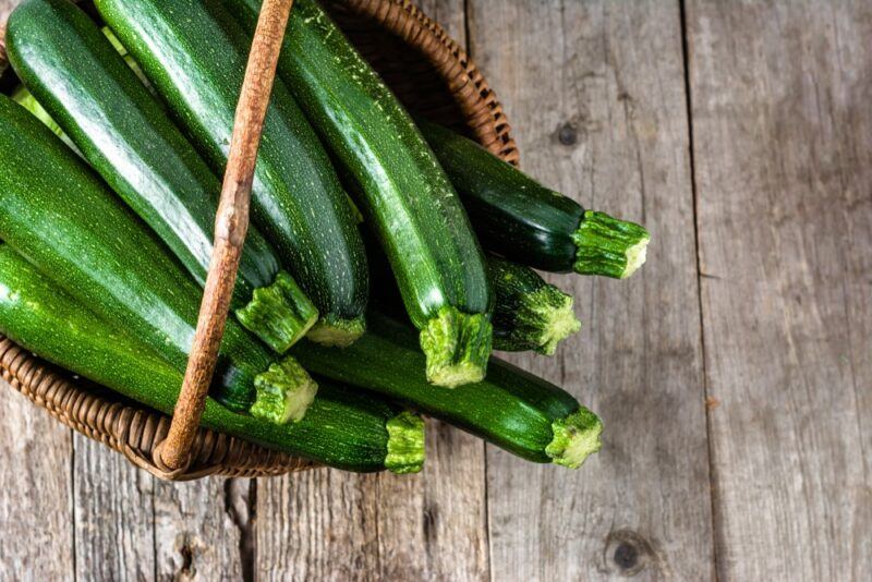 A basket filled with whole okra on a wooden table