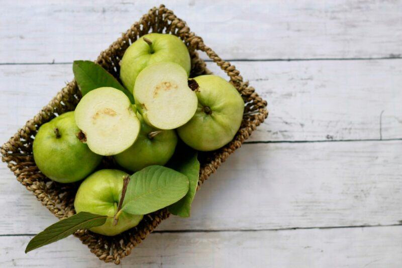 A wicker basket filled with fresh green guavas