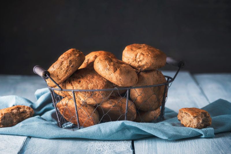 A basket of bread rolls in a rustic basket on a blue cloth