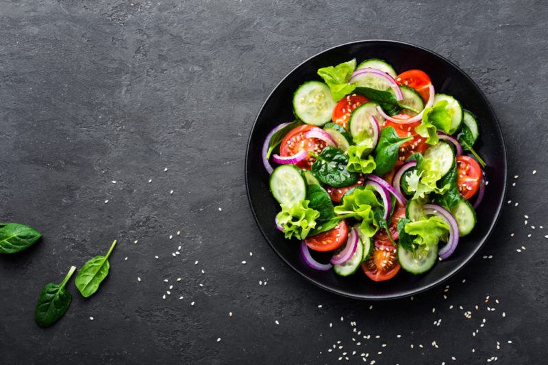 A black bowl containing a salad