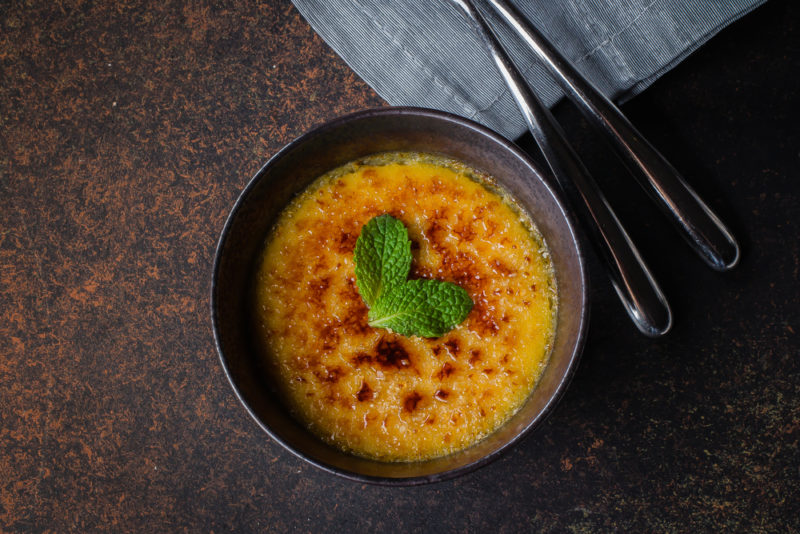 A black bowl filled with creme brulee